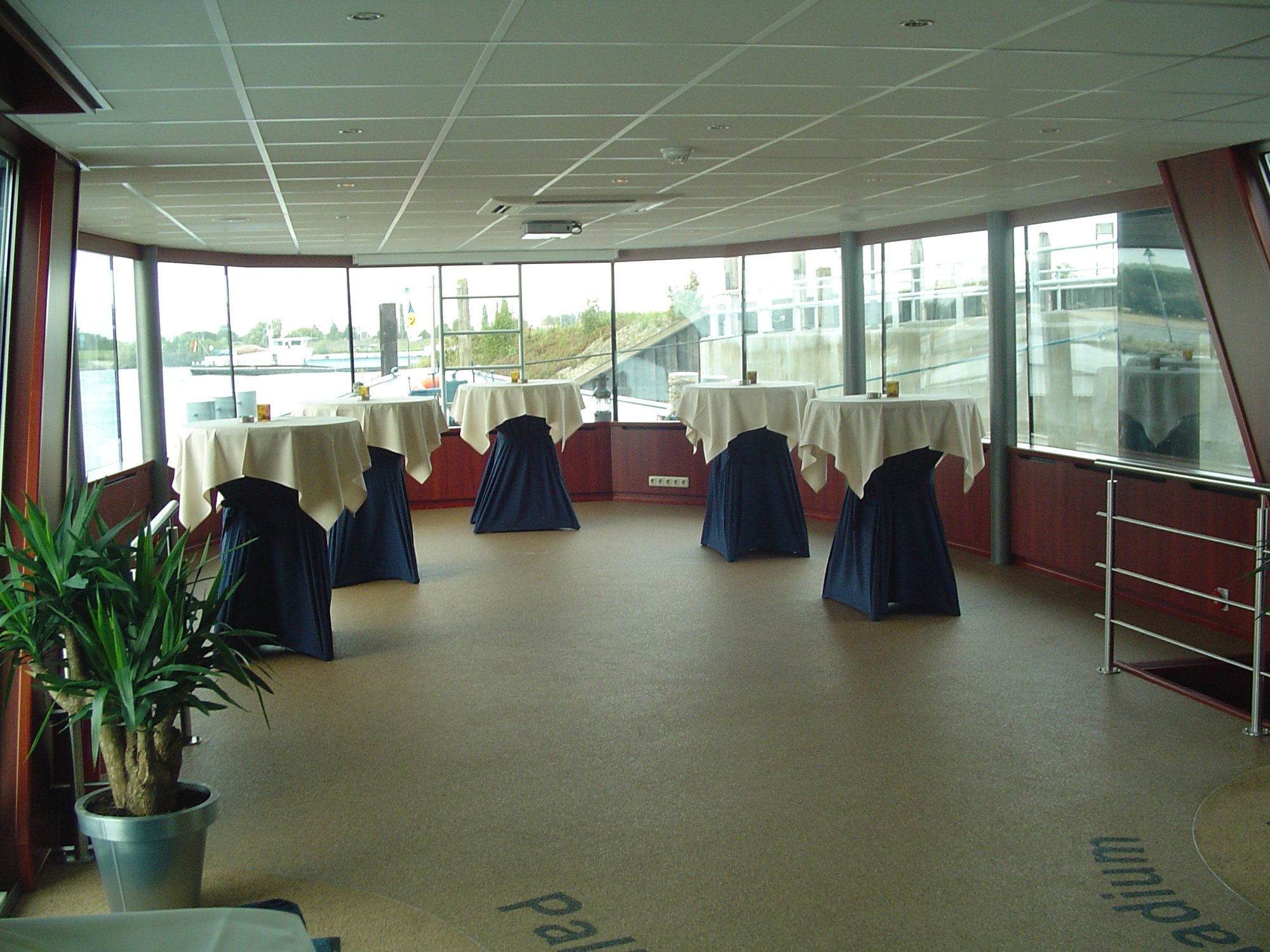 Lichte zaal met statafels en uitzicht op water