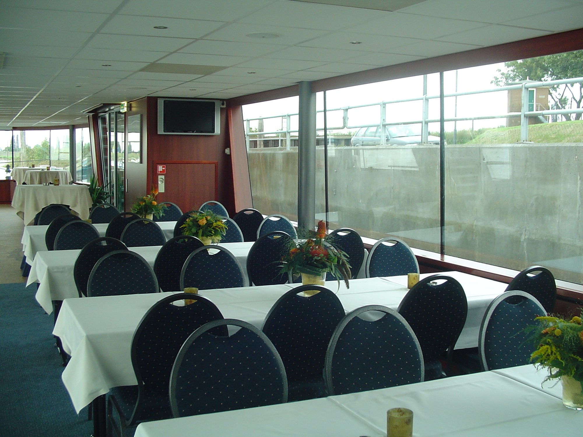 Ruime zaal met gedekte tafels en panoramaramen